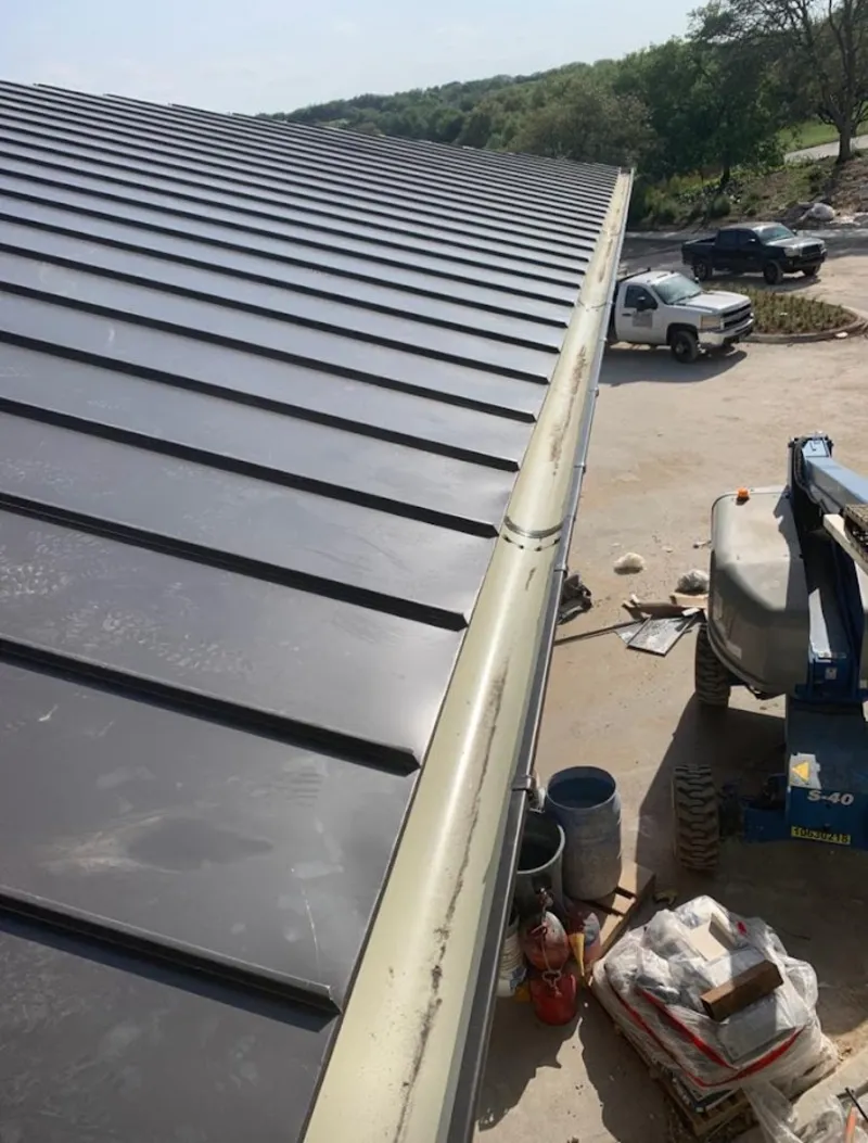 Standing seam panel and gutter detail on a metal roofing jobsite in Adams